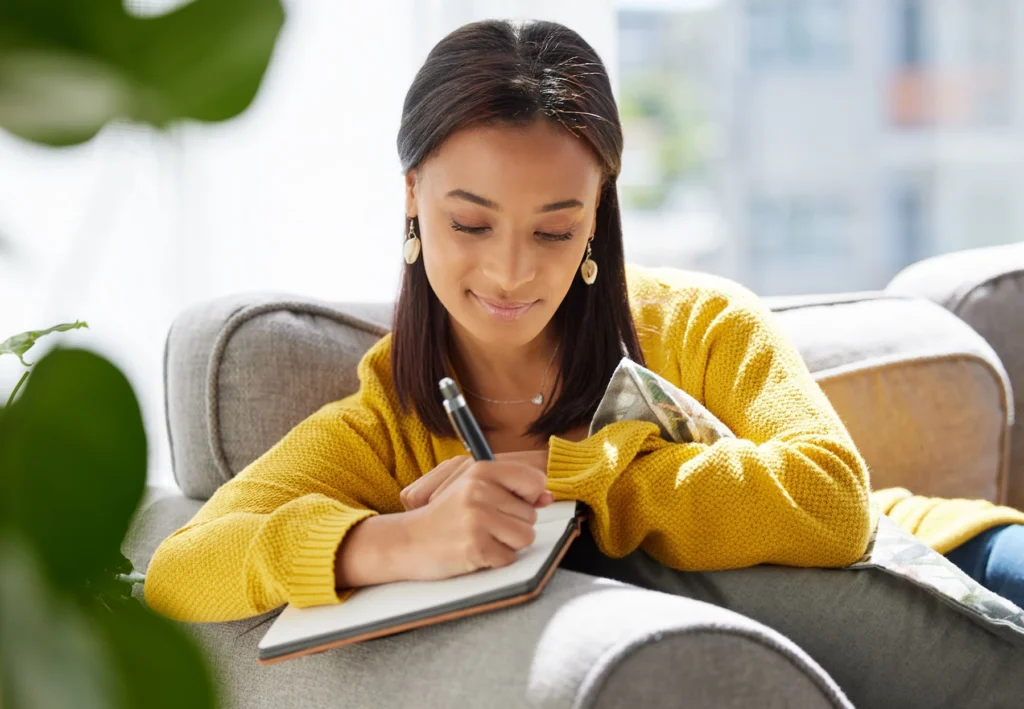 Woman writing in a notebook, relaxed.