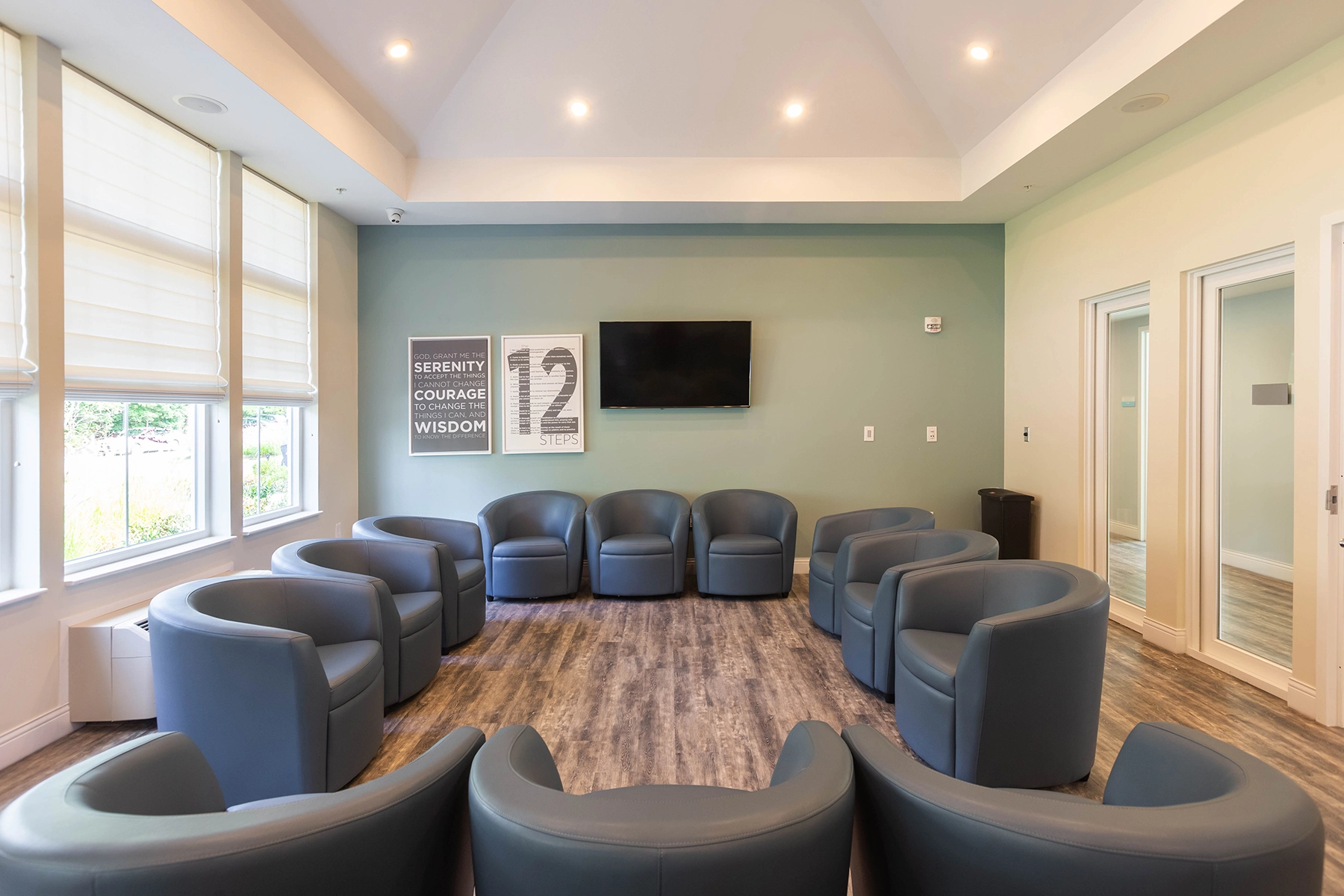 Group therapy room at Lighthouse with a circle of armchairs and 12-step artwork