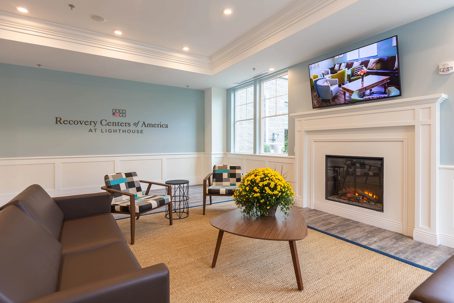 Fireplace lounge at Recovery Centers of America at Lighthouse with seating and fresh flowers