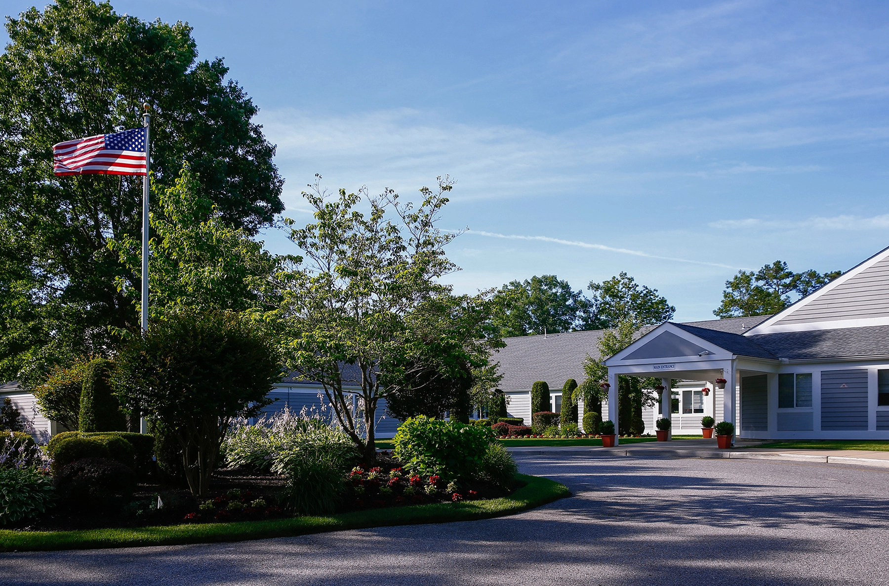Entrance drive at Lighthouse with an American flag and landscaped gardens