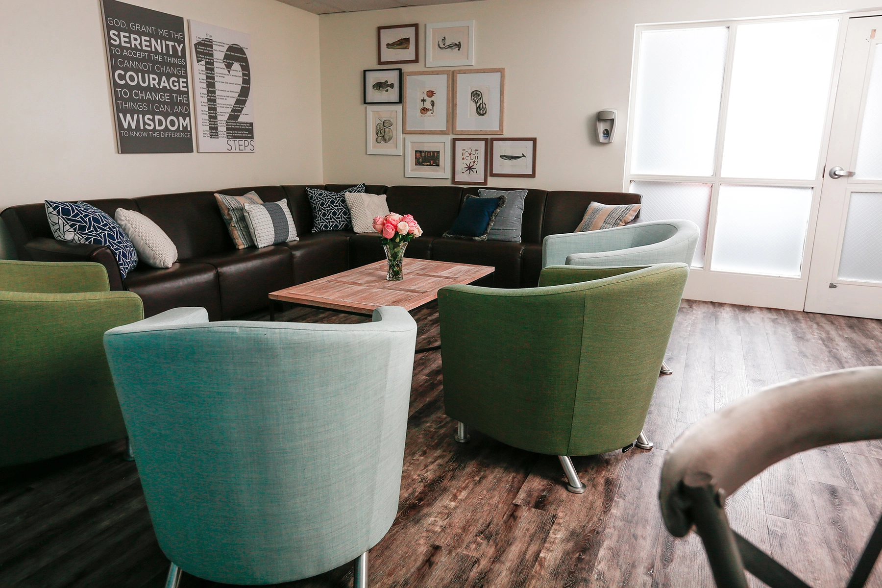 Group room at Lighthouse with a sectional sofa, armchairs and Serenity Prayer artwork