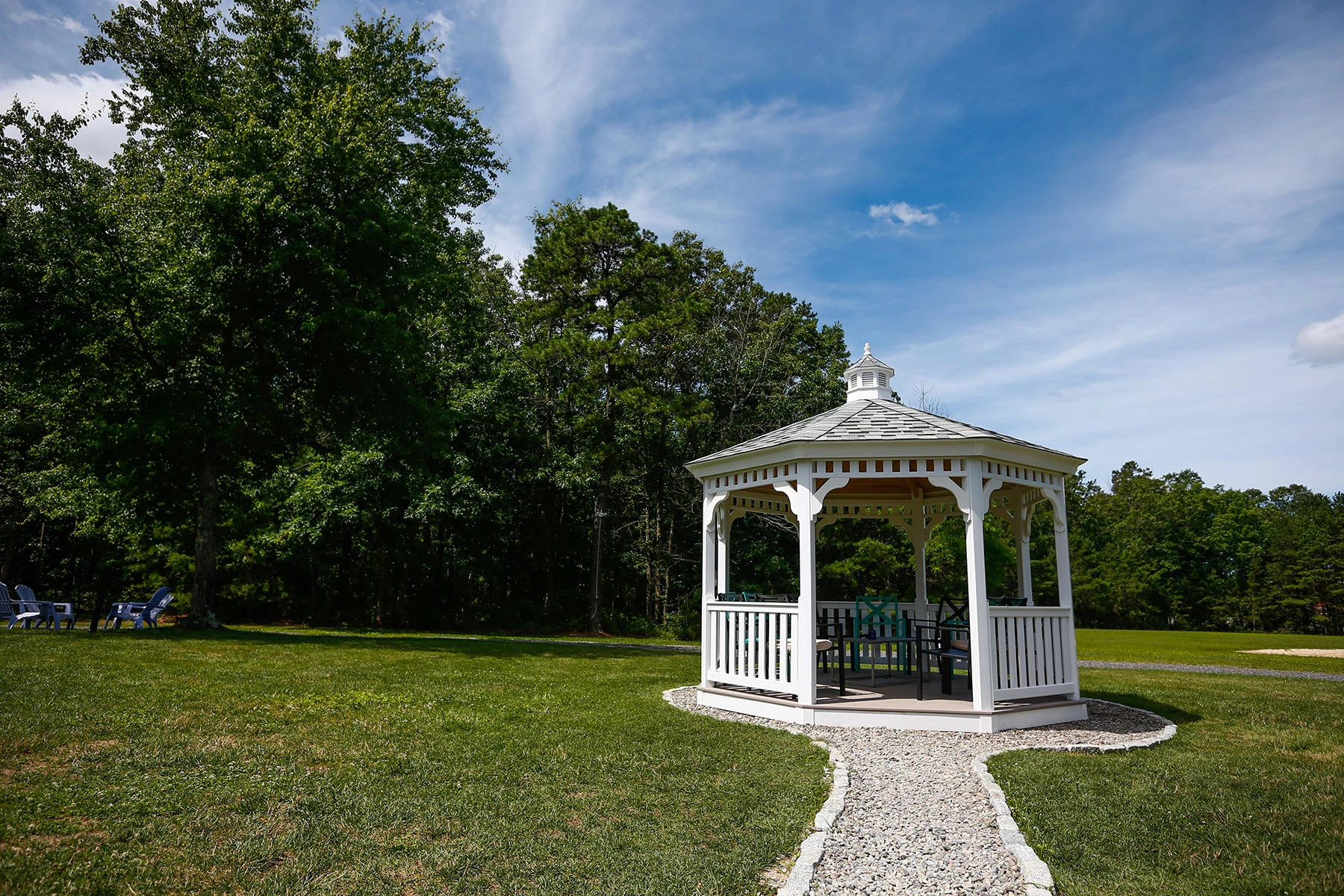 White gazebo on a lawn surrounded by trees at Lighthouse